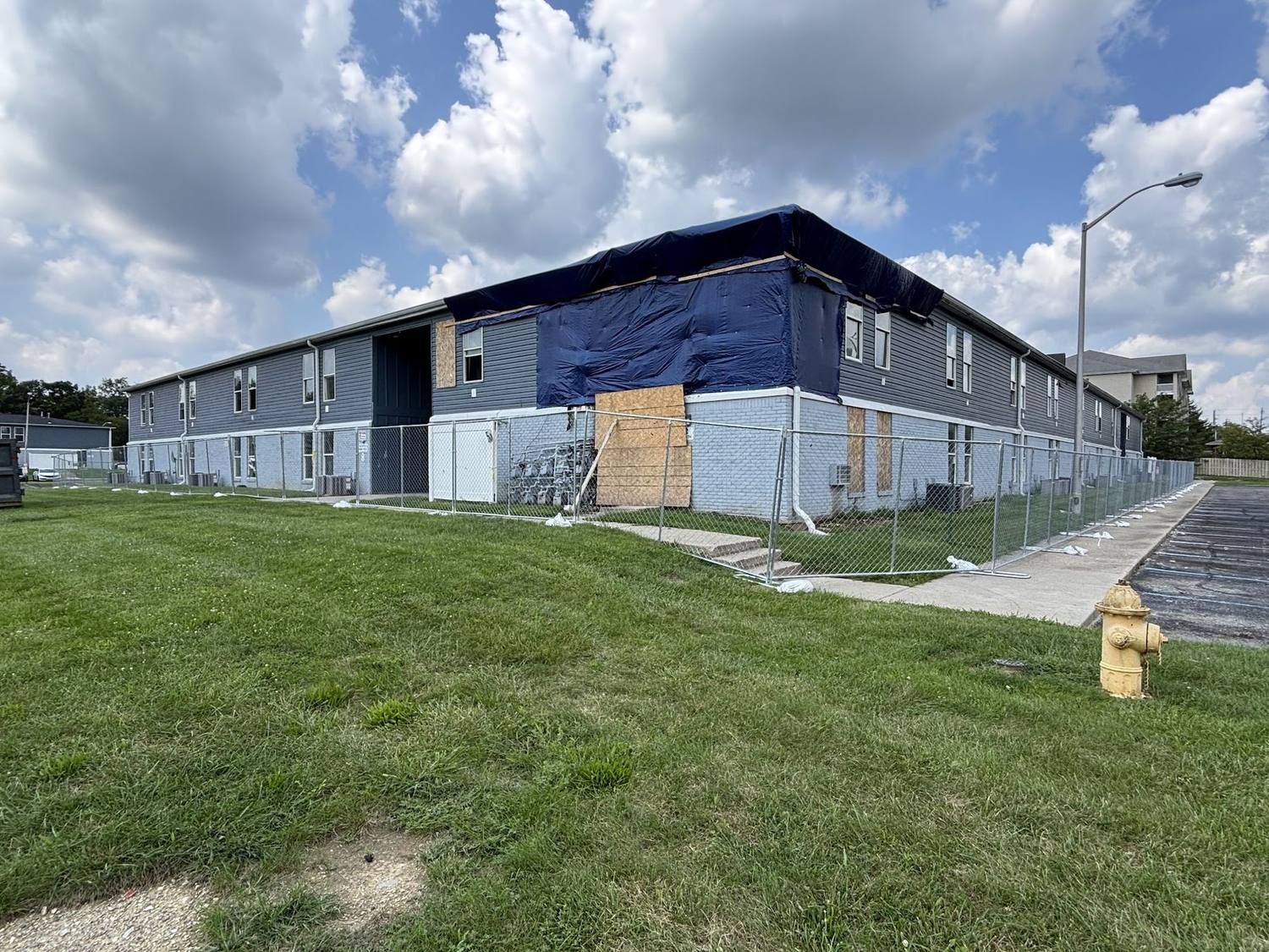 Temporary fence panels around an apartment building under construction with weather wrap on the walls