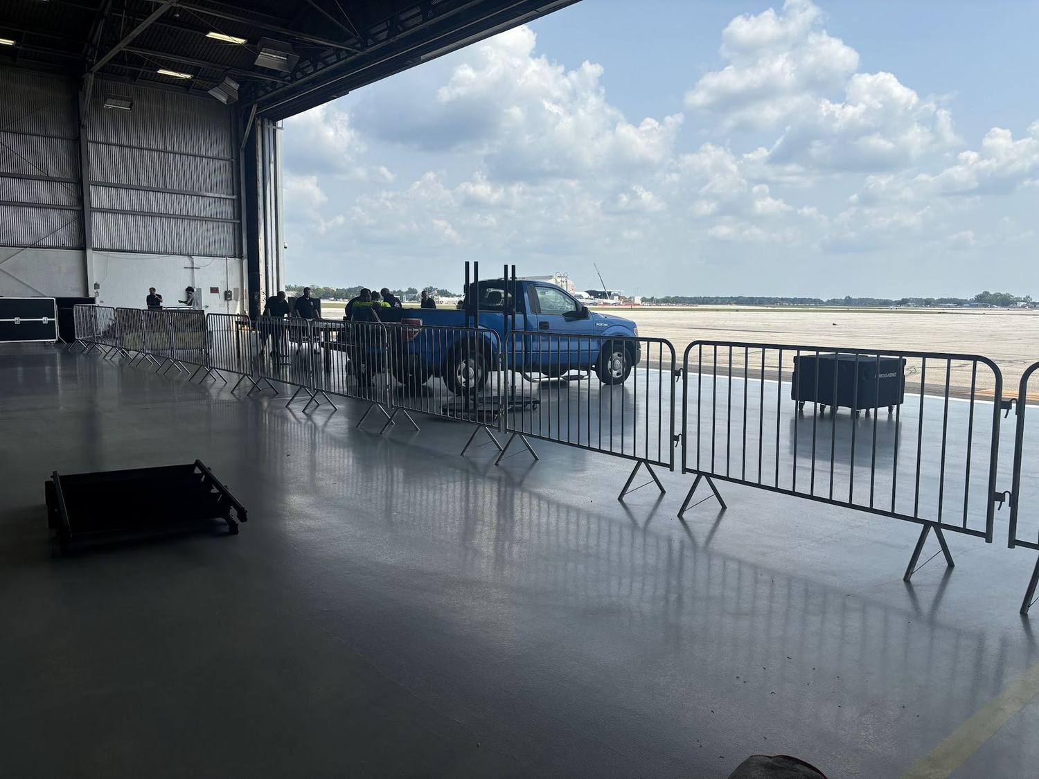 Crowd control barricades set inside a venue with a vehicle parked behind them