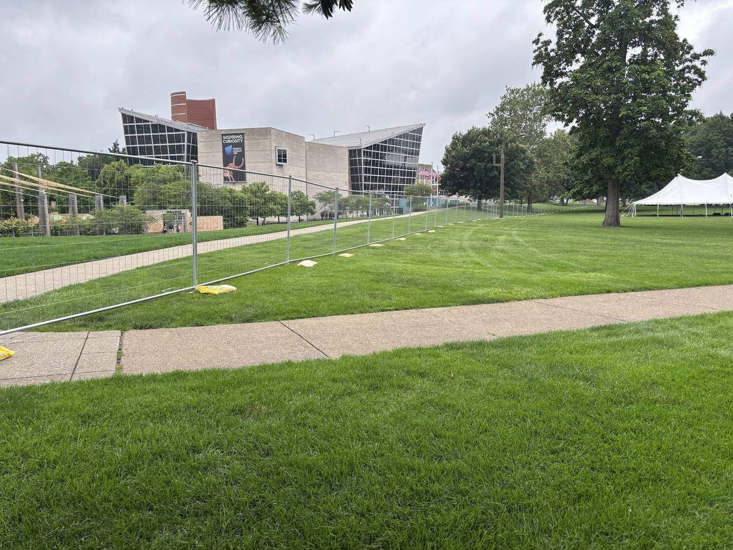 Temporary fence panels around an event lawn with a white tent behind them