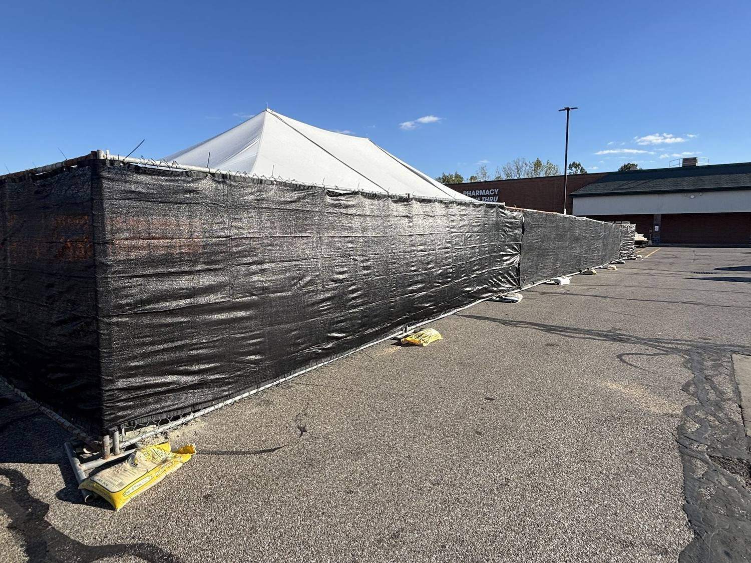 Windscreen fitted to temporary fence panels screening an event tent