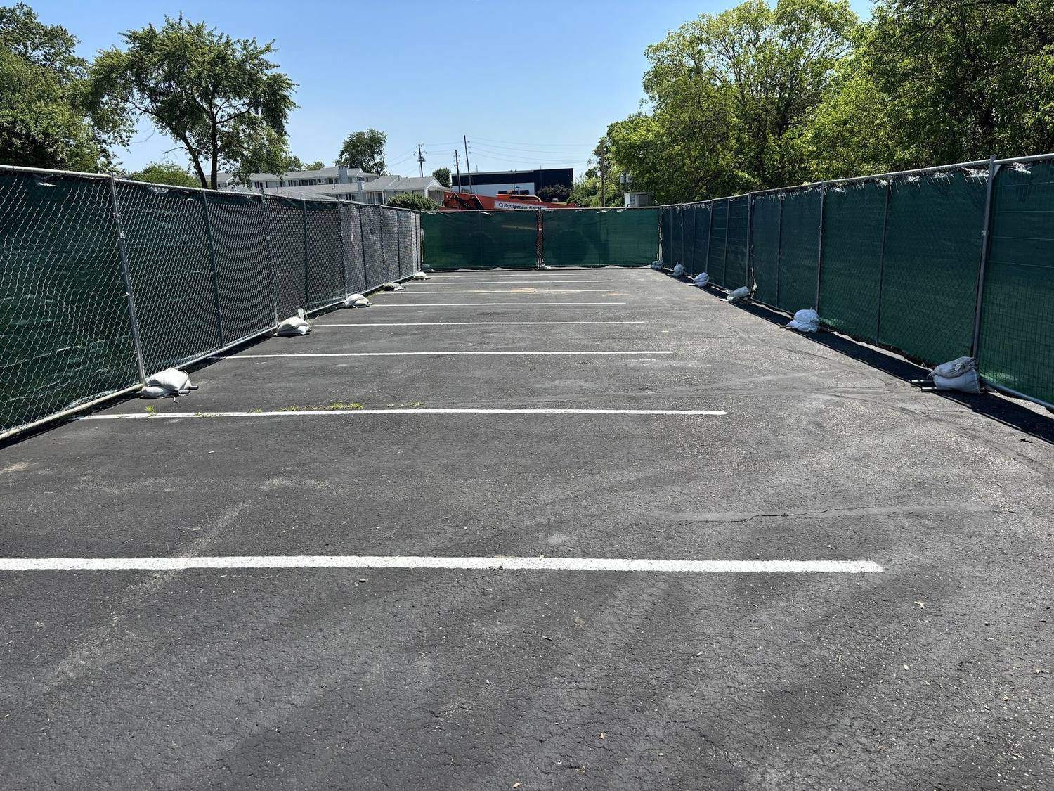 Green windscreen on temporary fence enclosing a paved parking lot