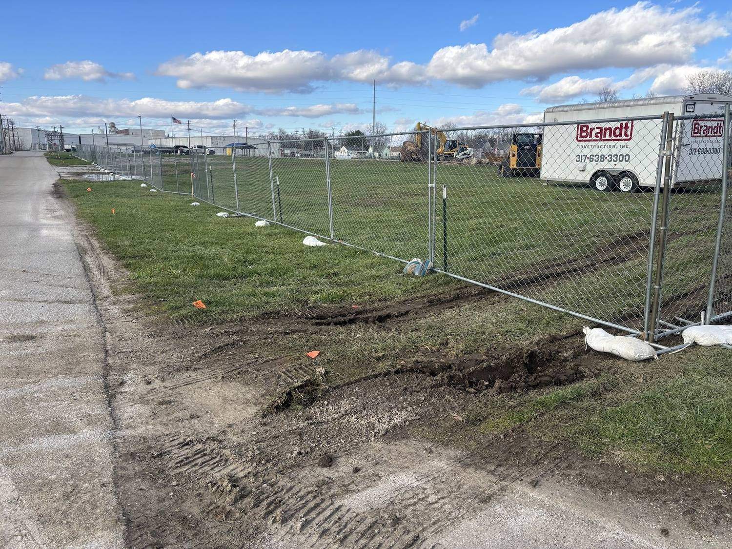 Temporary fence running along the muddy edge of an active construction site
