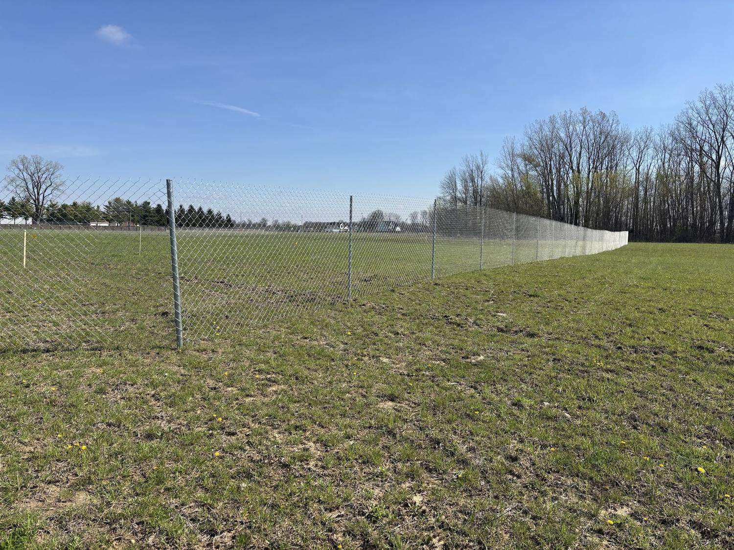 A long run of temporary fence panels across an open field