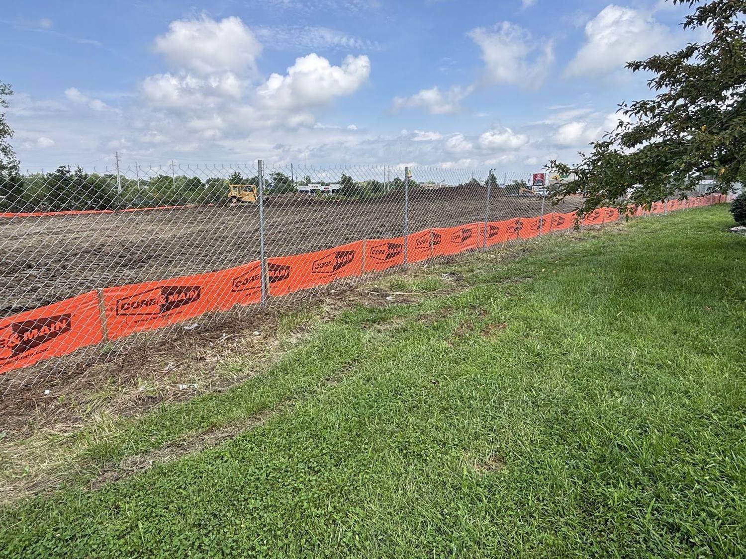 Safety fencing running across grass at the edge of a work area