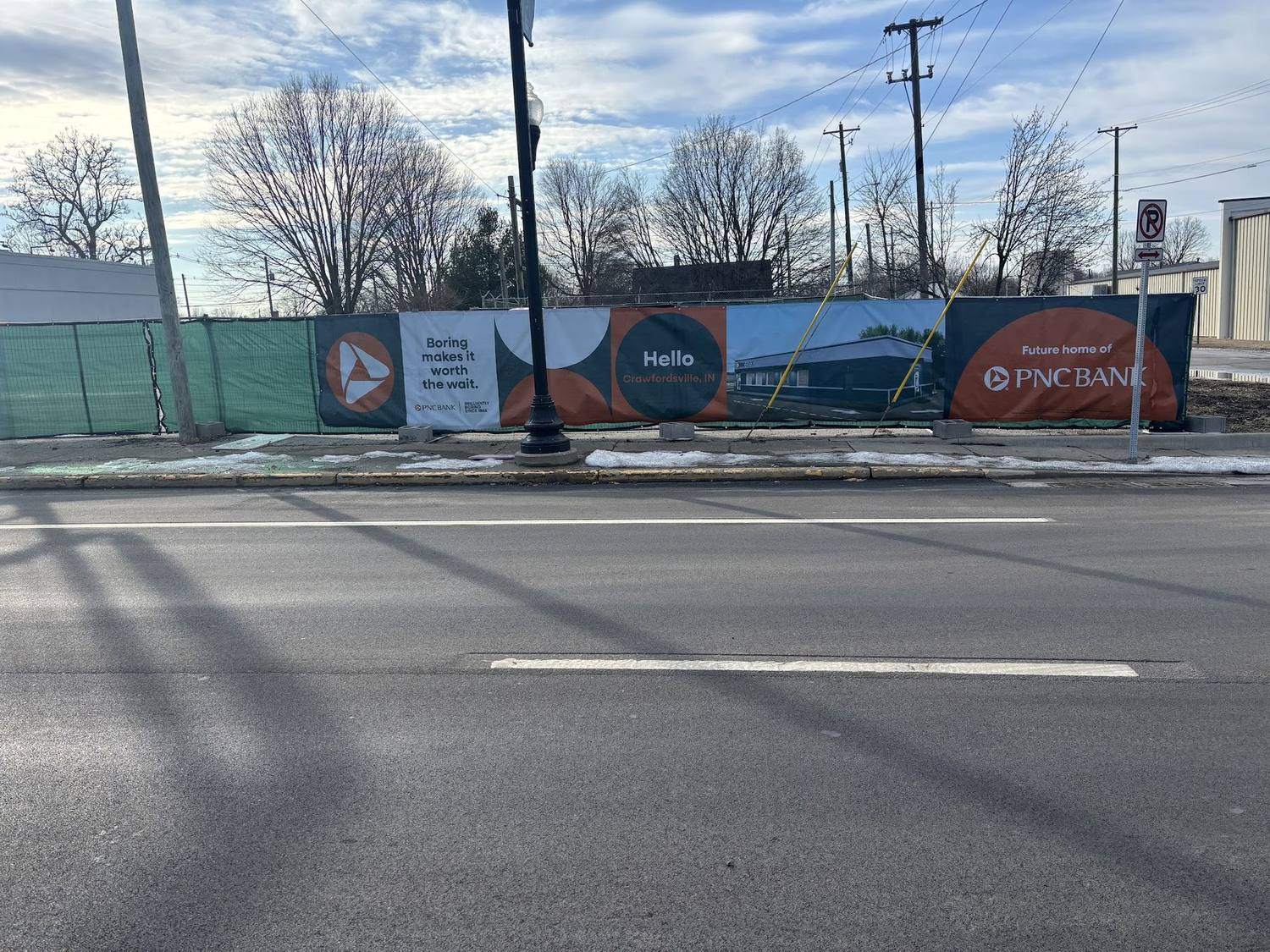 Printed windscreen panels carrying sponsor graphics on a temporary fence beside a road
