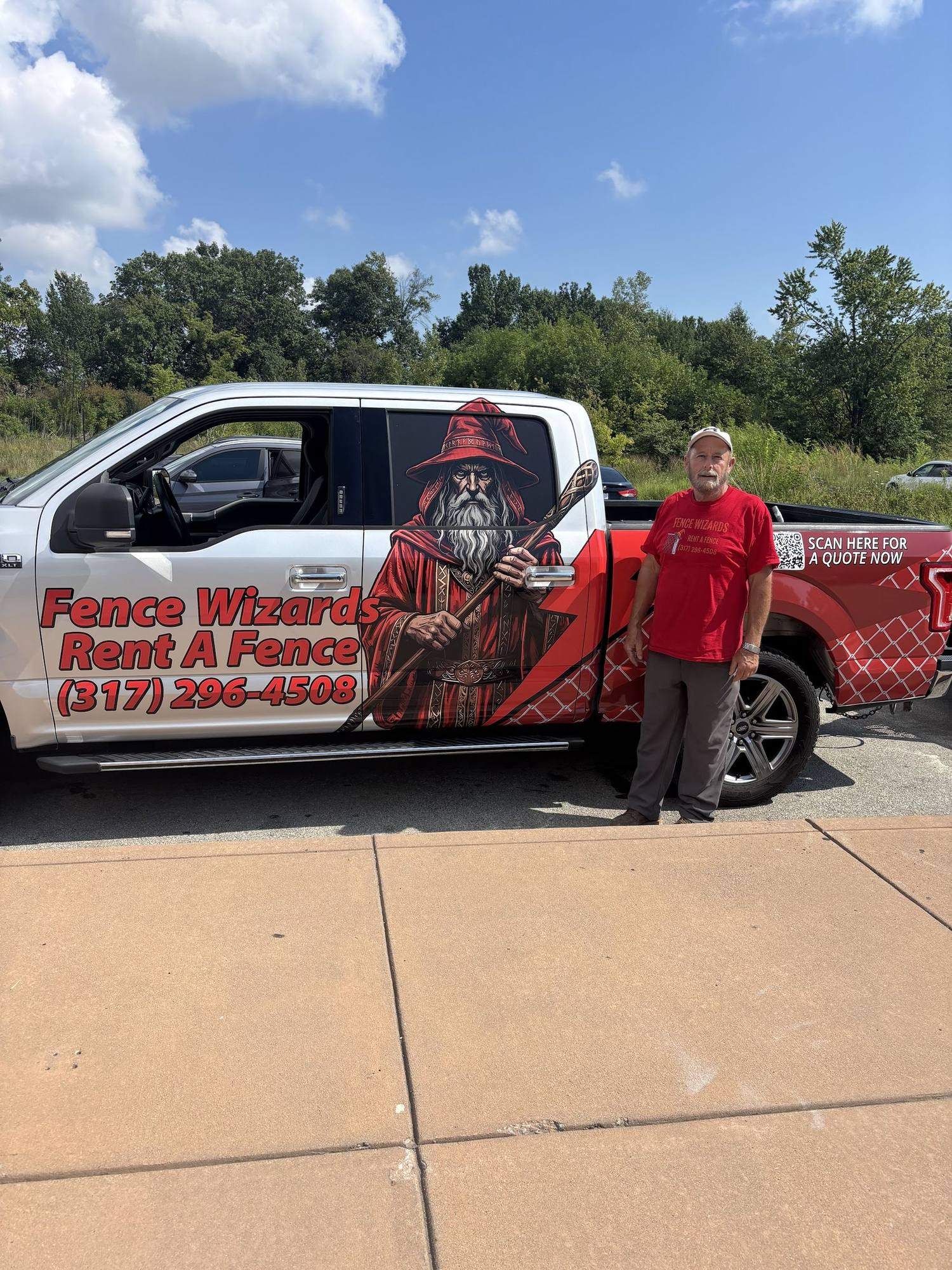 The side of a wrapped Fence Wizards truck on a job site
