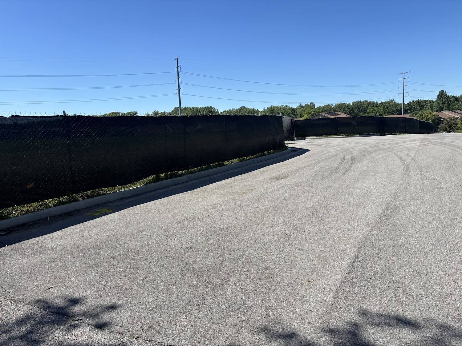 A black windscreen run enclosing a large paved lot